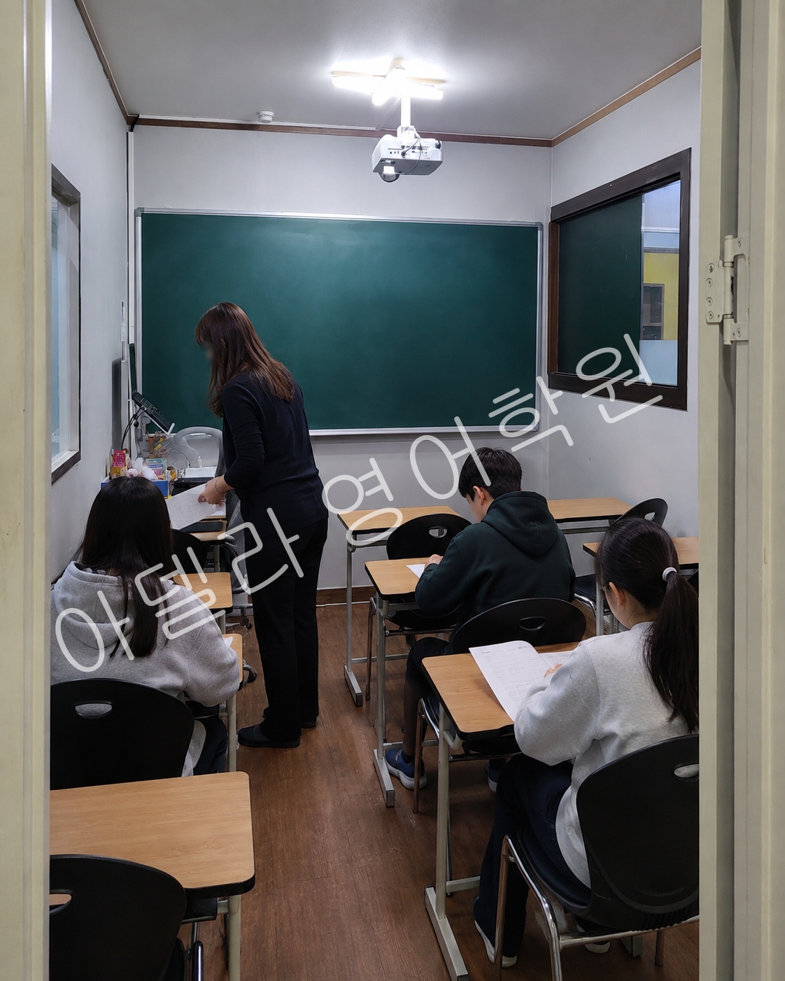수업 전 학습 안내를 듣는 학생들의 학원 공간 장면